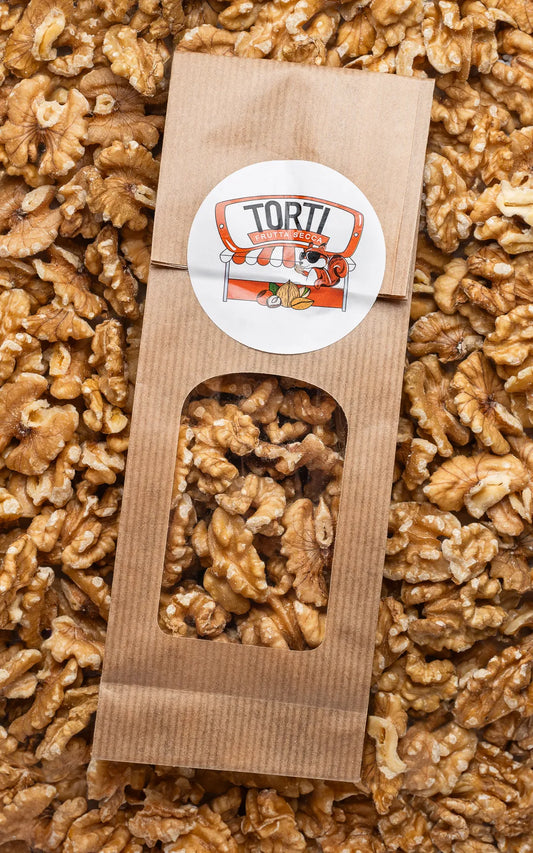 Noci sgusciate premium Torti Frutta Secca in busta di carta kraft con finestra trasparente, appoggiate su un letto di gherigli dorati sfusi — frutta secca naturale di qualità