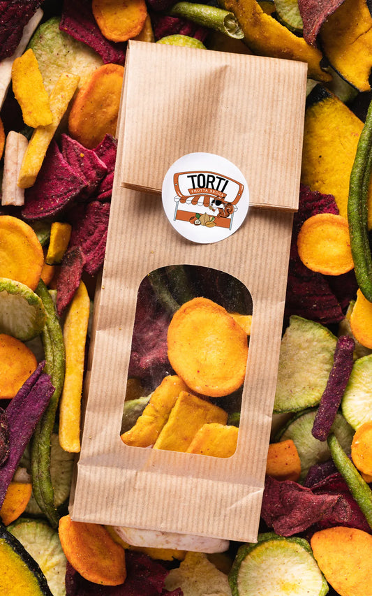 Sacchetto kraft Torti Frutta Secca con finestra trasparente contenente verdura chips disidratata premium: carote arancioni, barbabietole viola, zucchine verdi e patate dolci, circondato da un mix colorato di chips di verdure
